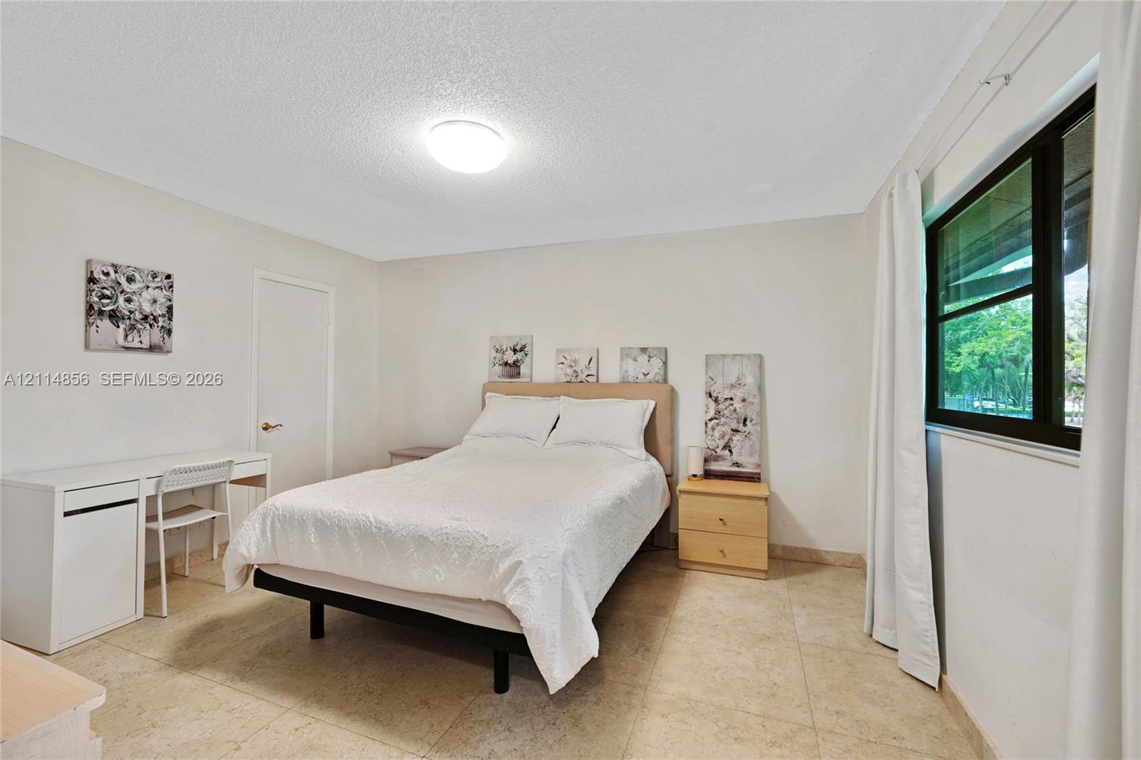 Neutral-toned room featuring stone-finish tile flooring, a large window with black framing, and a central flush-mount ceiling light