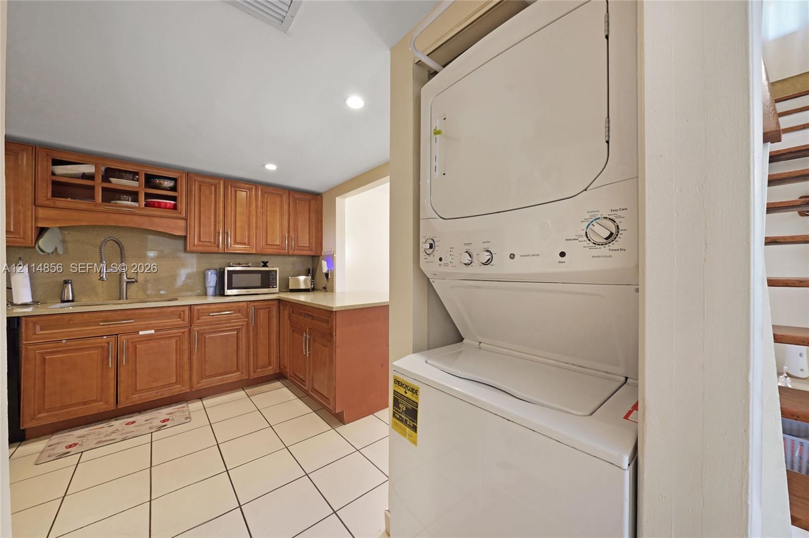Kitchen featuring wood cabinetry, recessed lighting, tile flooring, and integrated laundry unit Kitchen featuring wood cabinetry, recessed lighting, tile flooring, and integrated laundry unit