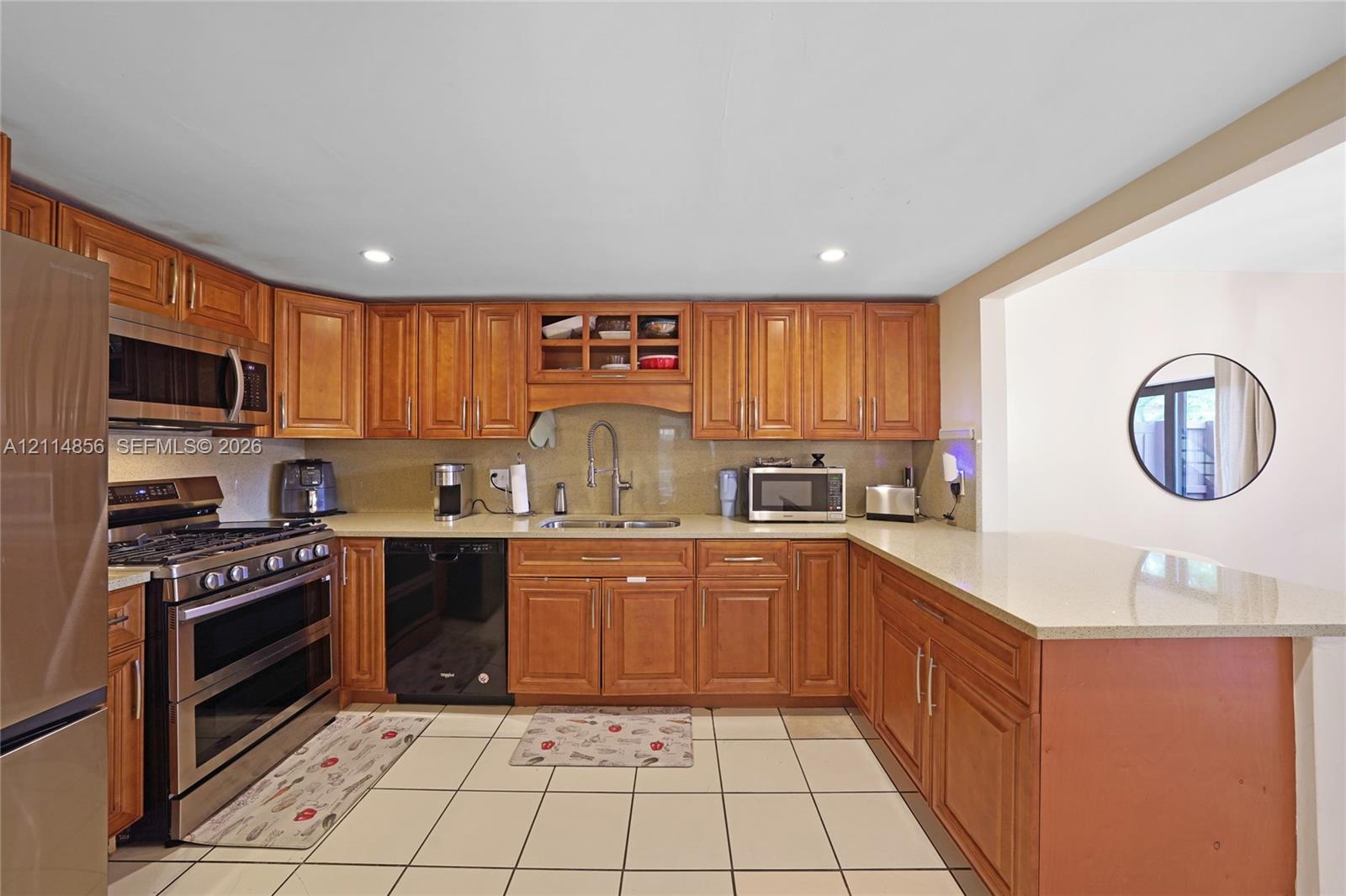 Kitchen featuring wood cabinetry, stone countertops, a stainless steel gas range, and ceramic tile flooring Kitchen featuring wood cabinetry, stone countertops, a stainless steel gas range, and ceramic tile flooring