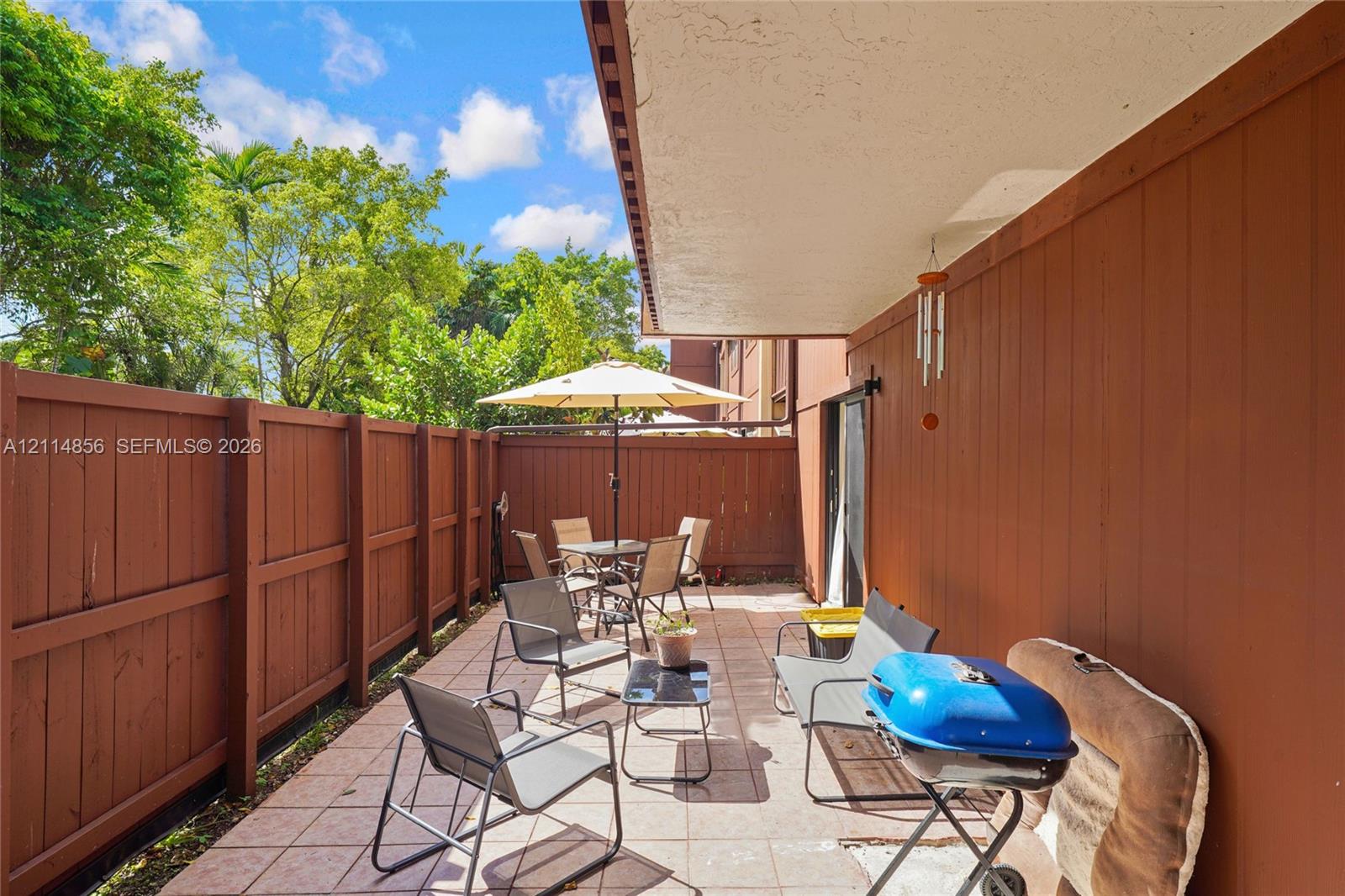 Covered patio featuring tiled flooring and a wood-slat privacy fence