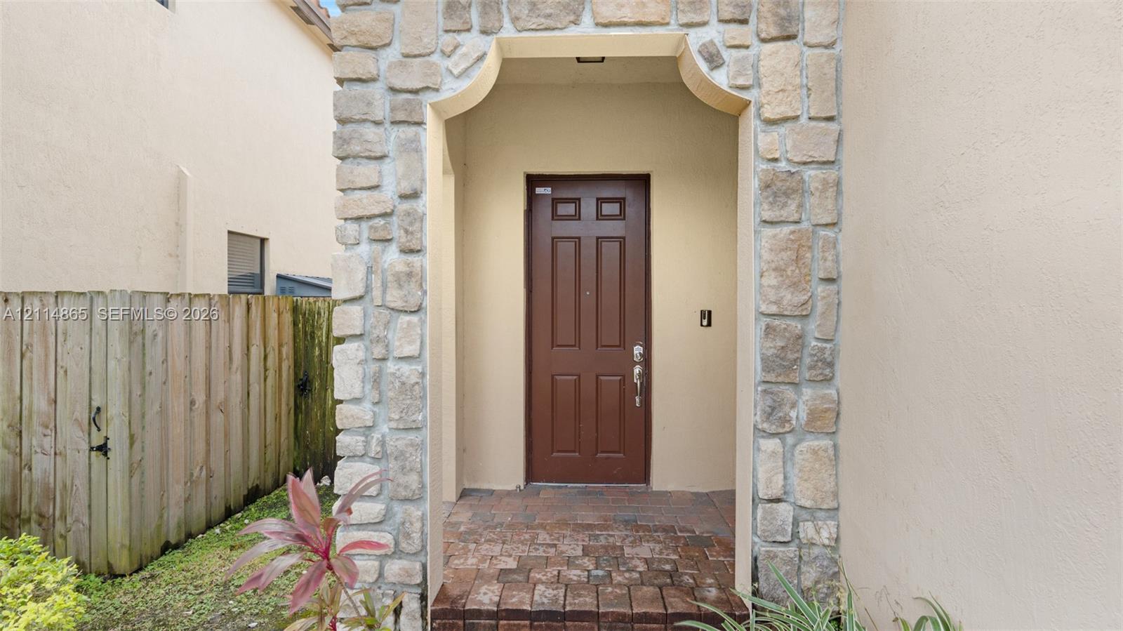 Entryway featuring a stone-clad arched portico, paver flooring, and a six-panel door