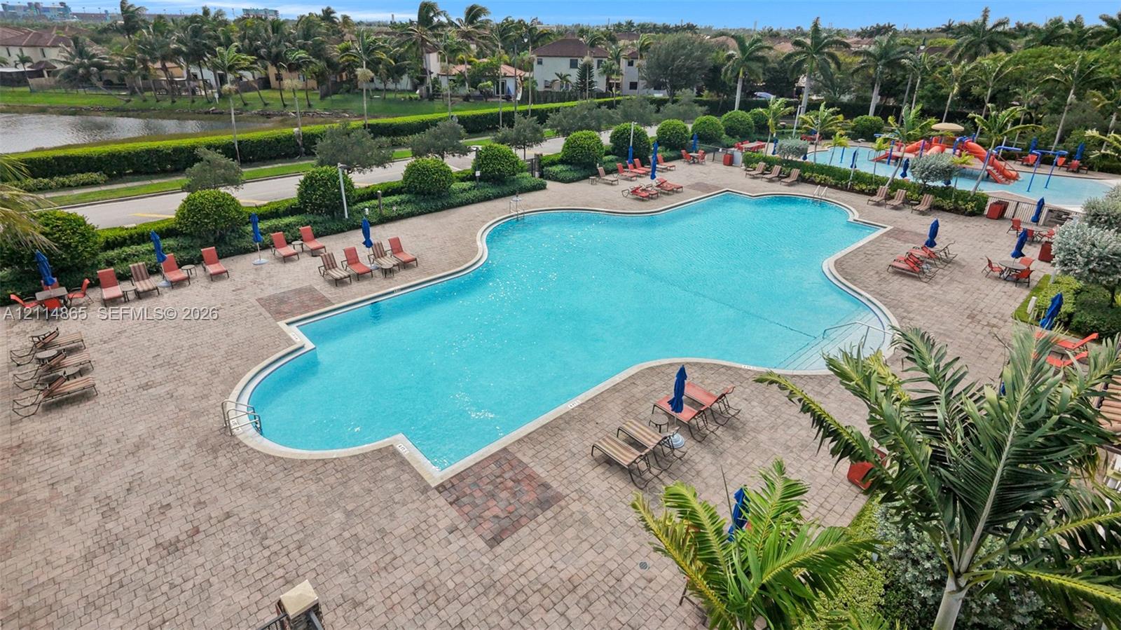 Large swimming pool featuring a brick-paved deck, secondary water play area, and perimeter landscaping