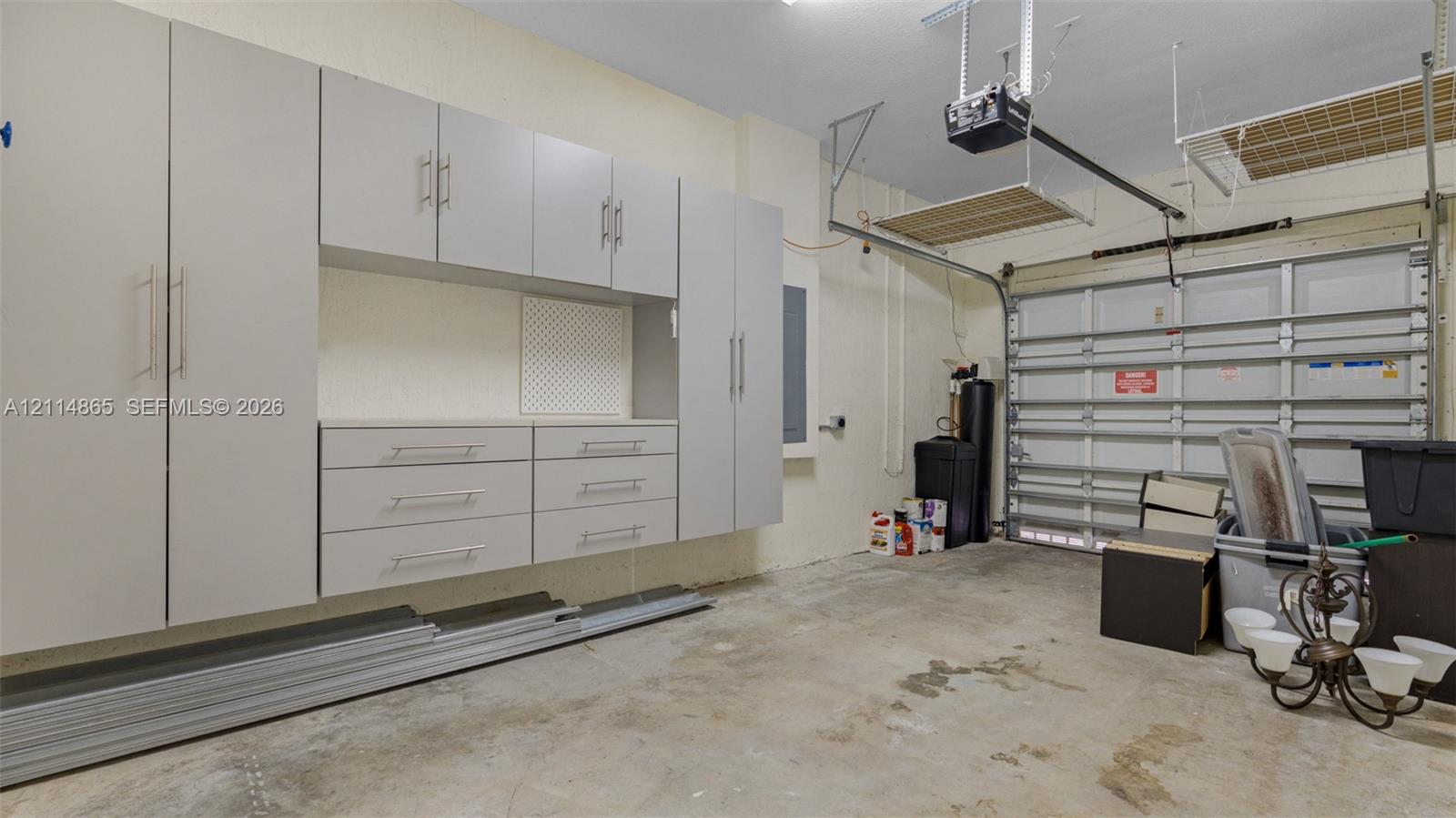 Garage featuring extensive wall-mounted cabinetry, integrated drawer storage, and overhead ceiling-mounted shelving