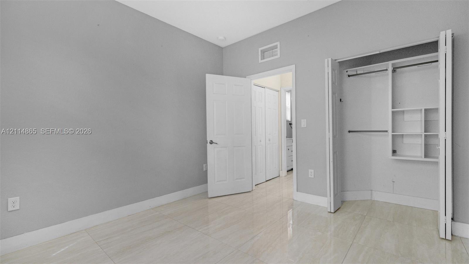 1st floor bedroom! Perfect guest/in-law space Interior space featuring neutral wall paint, polished tile flooring, and a walk-in closet with built-in shelving