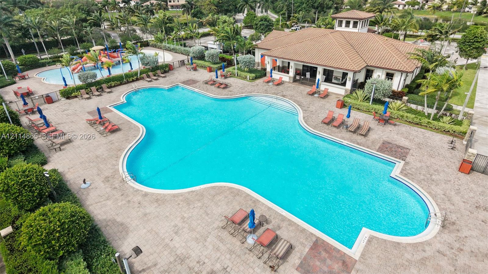 Community amenities featuring a large swimming pool with paver decking, a secondary splash pool with play structures, and a clubhouse with a multi-hipped roof