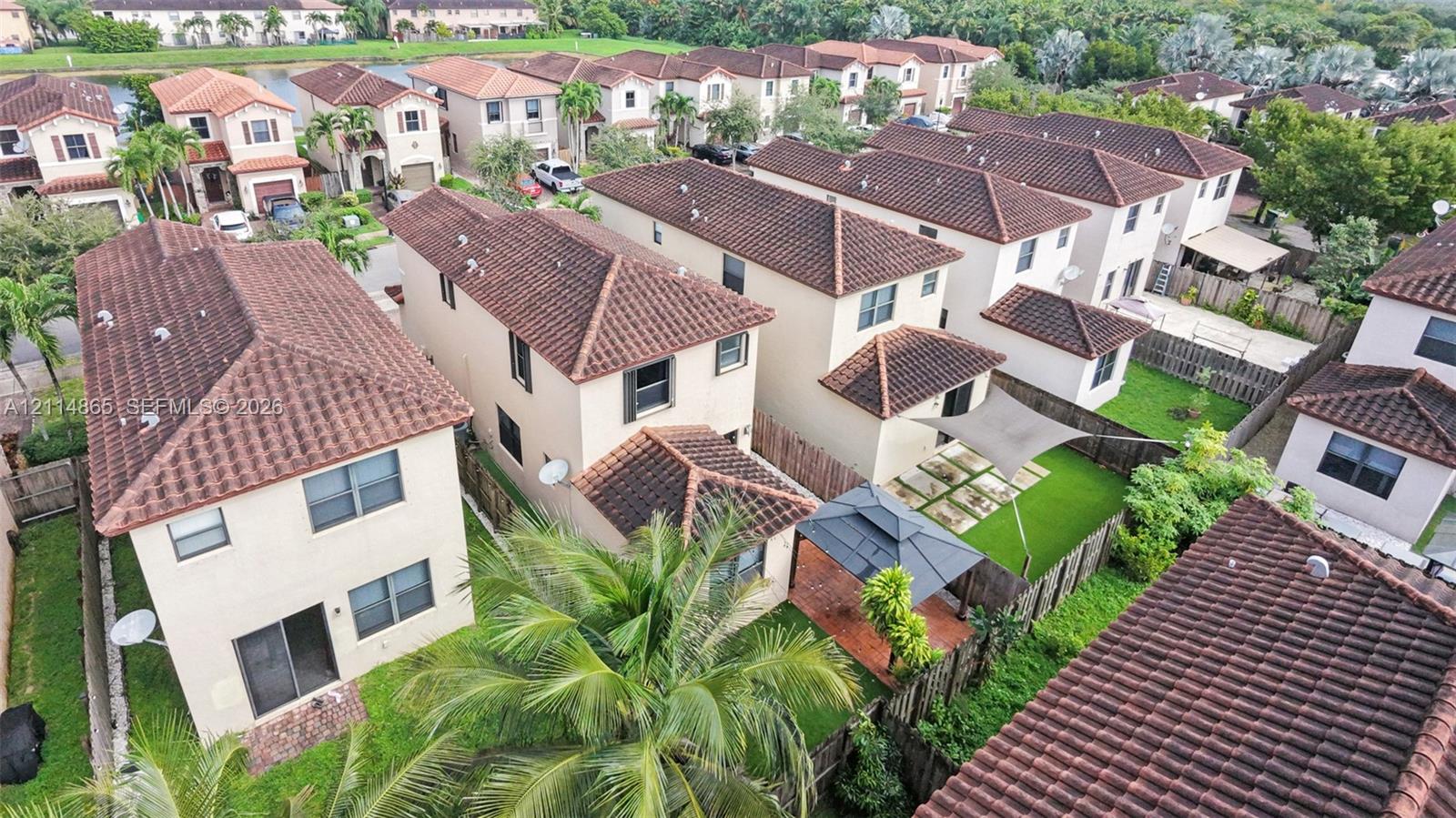 Aerial perspective of a multi-story residential community featuring tile roofs, stucco exteriors, and fenced backyards