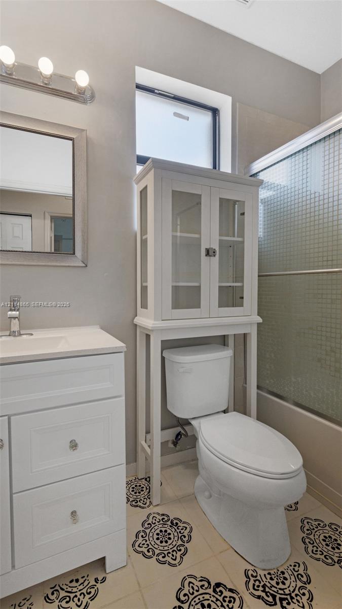 2nd floor full Bathroom featuring white shaker-style cabinetry with a smooth surface countertop, patterned tile flooring, a multi-light wall fixture, and a glass-enclosed shower