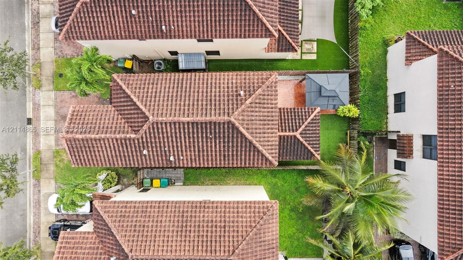 Aerial perspective featuring a tile roof, concrete driveway, and maintained lawn area