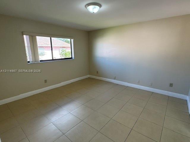 Neutral-toned room featuring large-format ceramic floor tile, a ceiling-mounted light fixture, and a single-pane window with vertical blinds