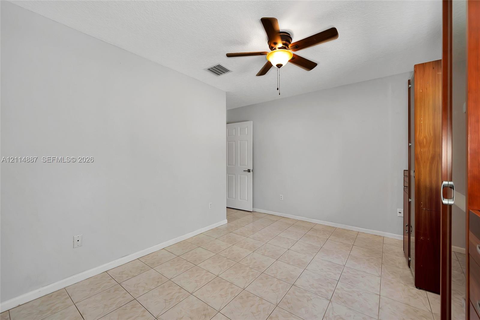 Neutral wall tones, ceramic tile flooring, ceiling fan with light fixture, and built-in closet cabinetry