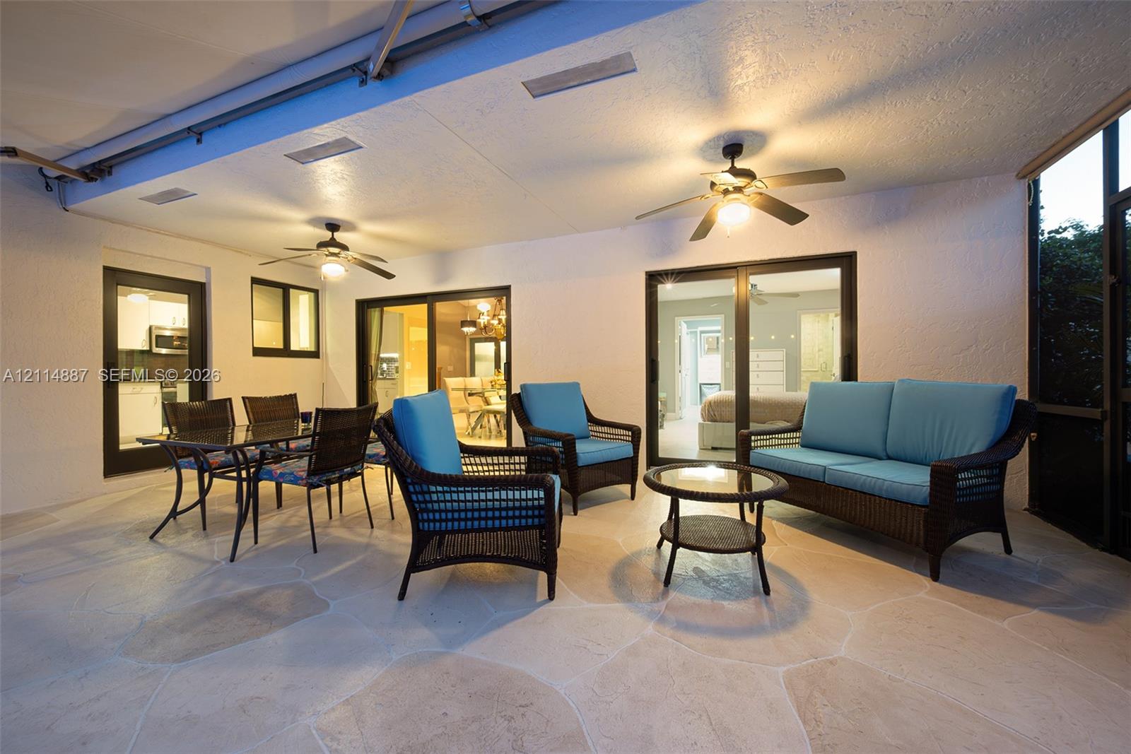 Covered patio featuring flagstone flooring, two ceiling fans, and multiple sliding glass door entries