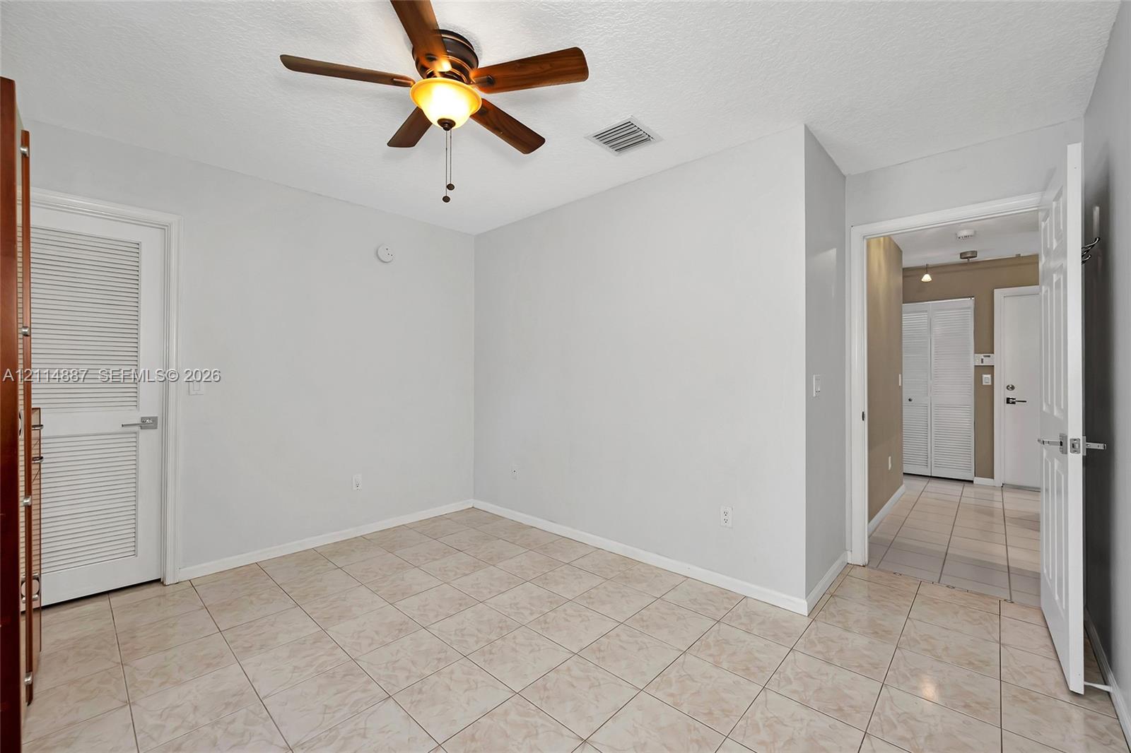 Ceramic tile flooring, ceiling fan with integrated lighting, and louvered closet door