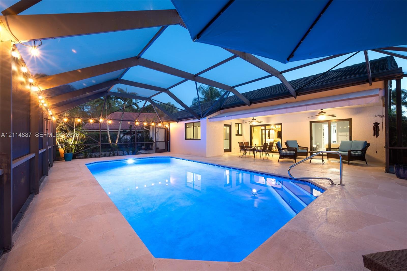 Screened-in pool area featuring a stone-paver pool deck, integrated pool steps, and an expansive overhead structural cage