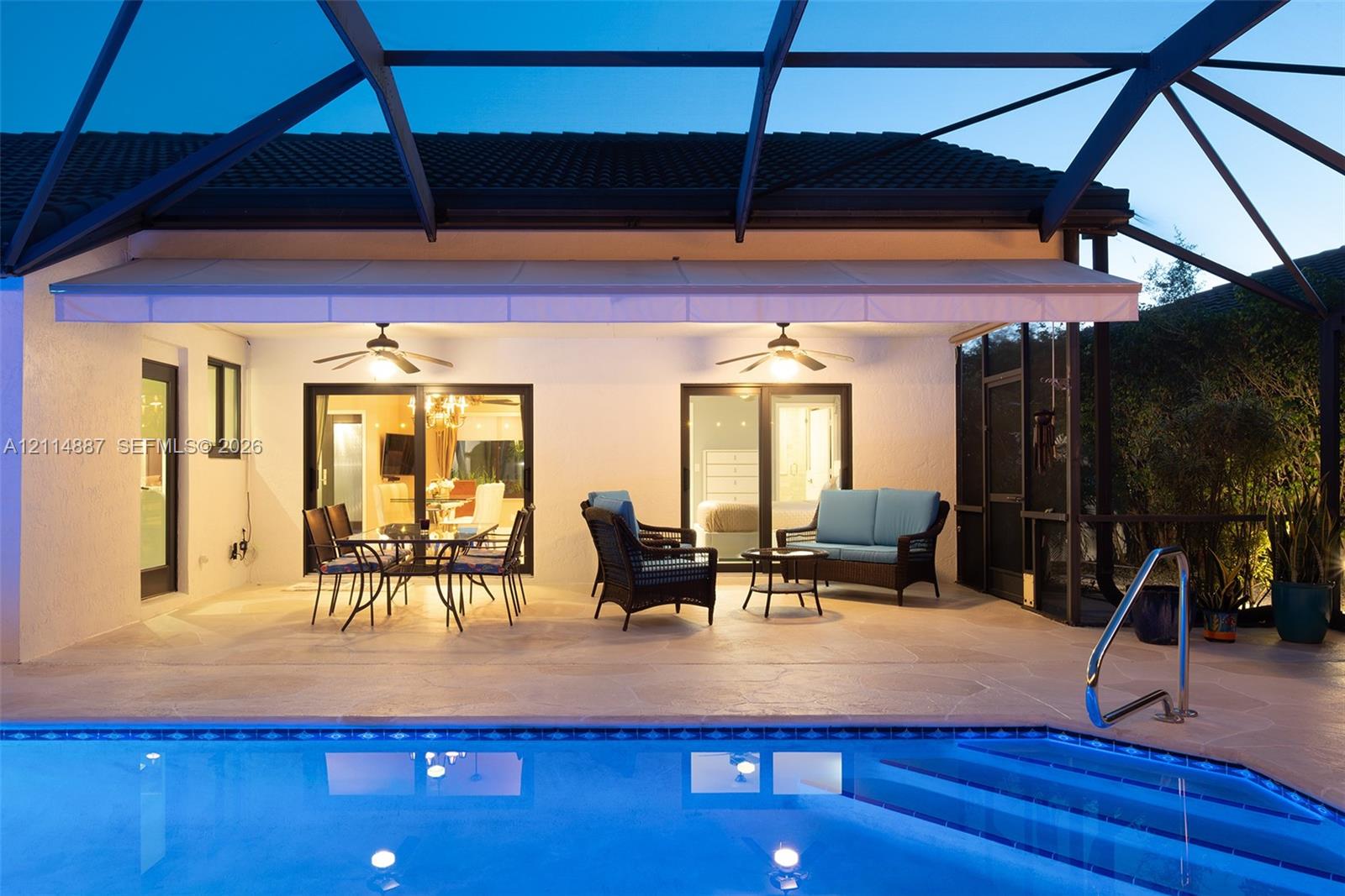 Covered patio featuring a retractable awning, two ceiling fans, screen enclosure, and direct access to a swimming pool with integrated steps