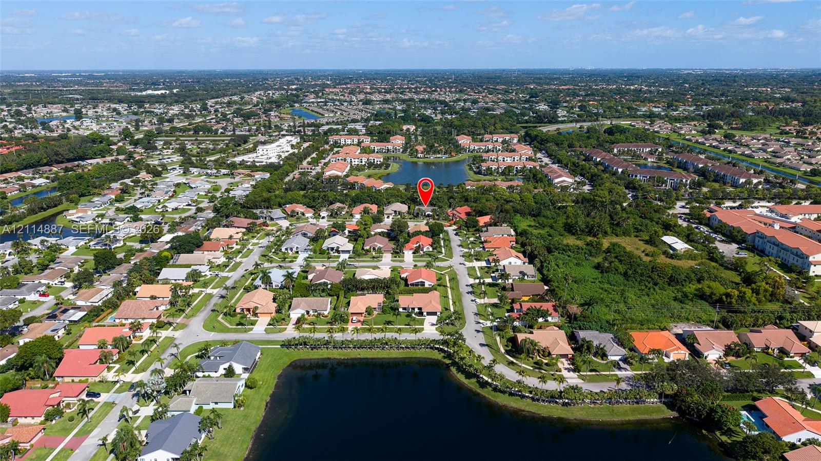Aerial perspective of a residential subdivision featuring paved streets, tile-roofed structures, and bodies of water