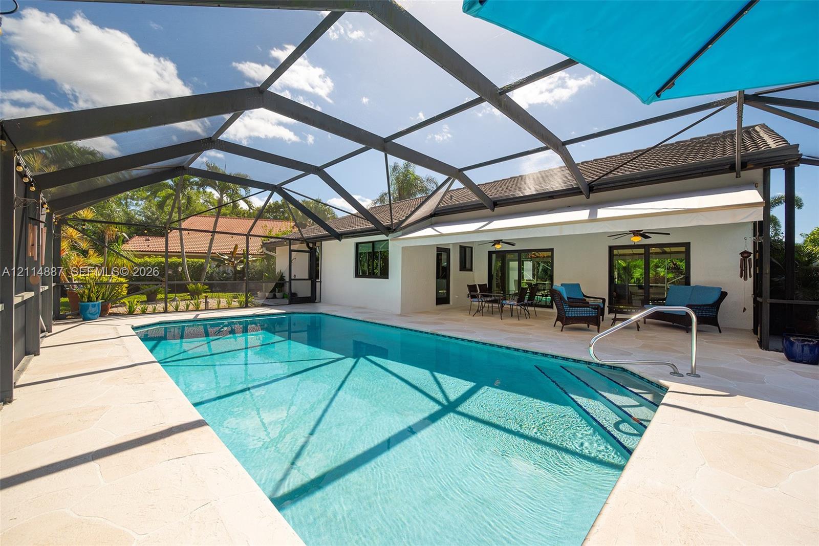 Screened lanai featuring a swimming pool, stone-paver decking, and a retractable awning Screened lanai featuring a swimming pool, stone-paver decking, and a retractable awning