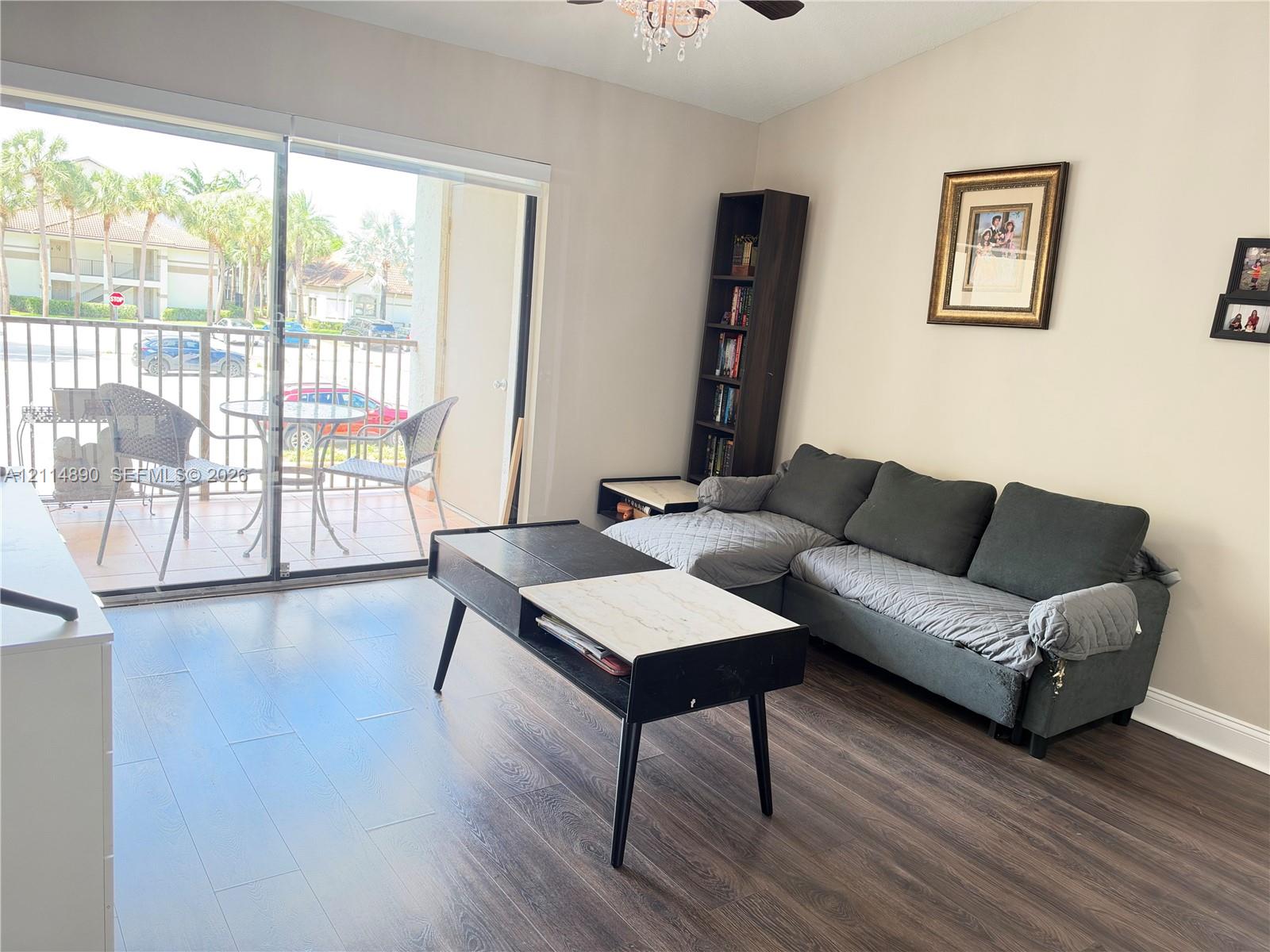 Wood-finish flooring, sliding glass patio door, ceiling-mounted light fixture, and tiled exterior balcony