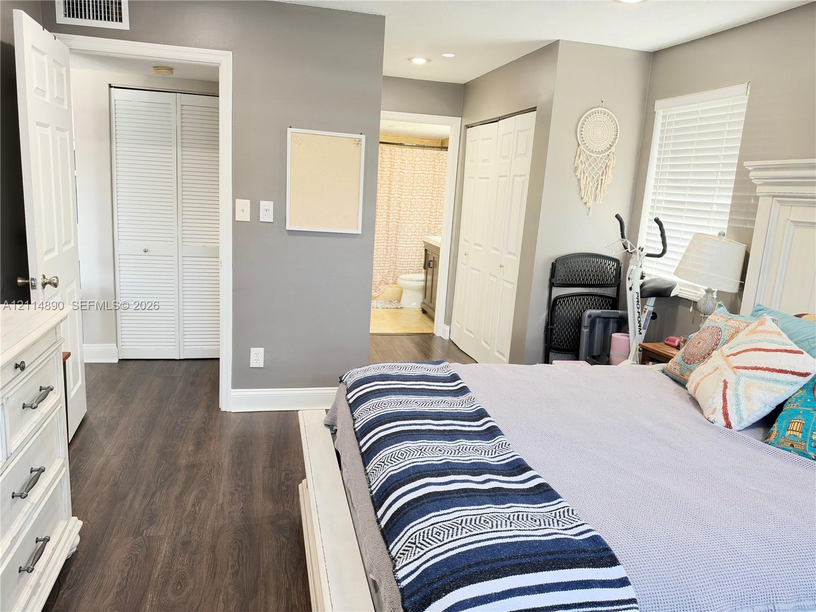 Bedroom featuring wood-finish flooring, two sets of louvered bifold closet doors, recessed lighting, and horizontal blinds