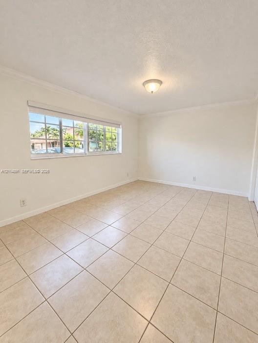 Neutral interior space featuring large-format ceramic tile flooring, multi-pane windows, crown molding, and a central dome-style light fixture Neutral interior space featuring large-format ceramic tile flooring, multi-pane windows, crown molding, and a central dome-style light fixture