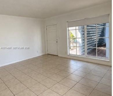 Interior space featuring neutral-toned tile flooring, multi-pane windows with a roller shade, and a paneled entry door