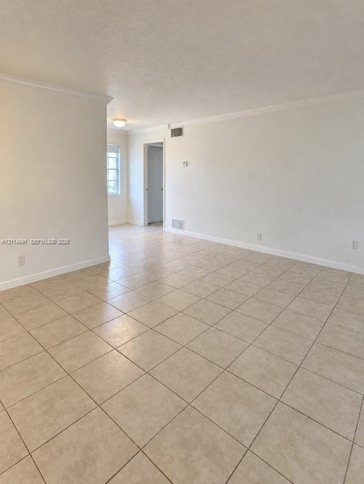 Neutral interior space featuring large-format ceramic tile flooring, crown molding, and smooth-finish walls Neutral interior space featuring large-format ceramic tile flooring, crown molding, and smooth-finish walls