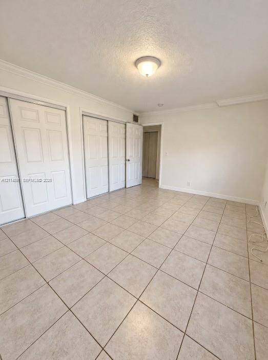 Neutral-toned ceramic tile flooring, multi-panel sliding closet doors, and crown molding detail Neutral-toned ceramic tile flooring, multi-panel sliding closet doors, and crown molding detail