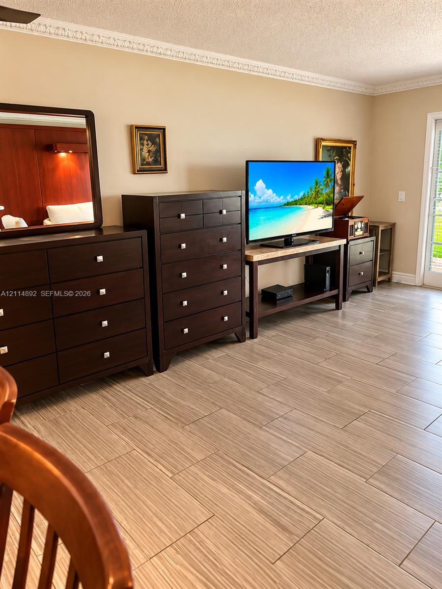 Neutral wall tones accented by crown molding, wood-finish tile flooring, and a glass-paneled door