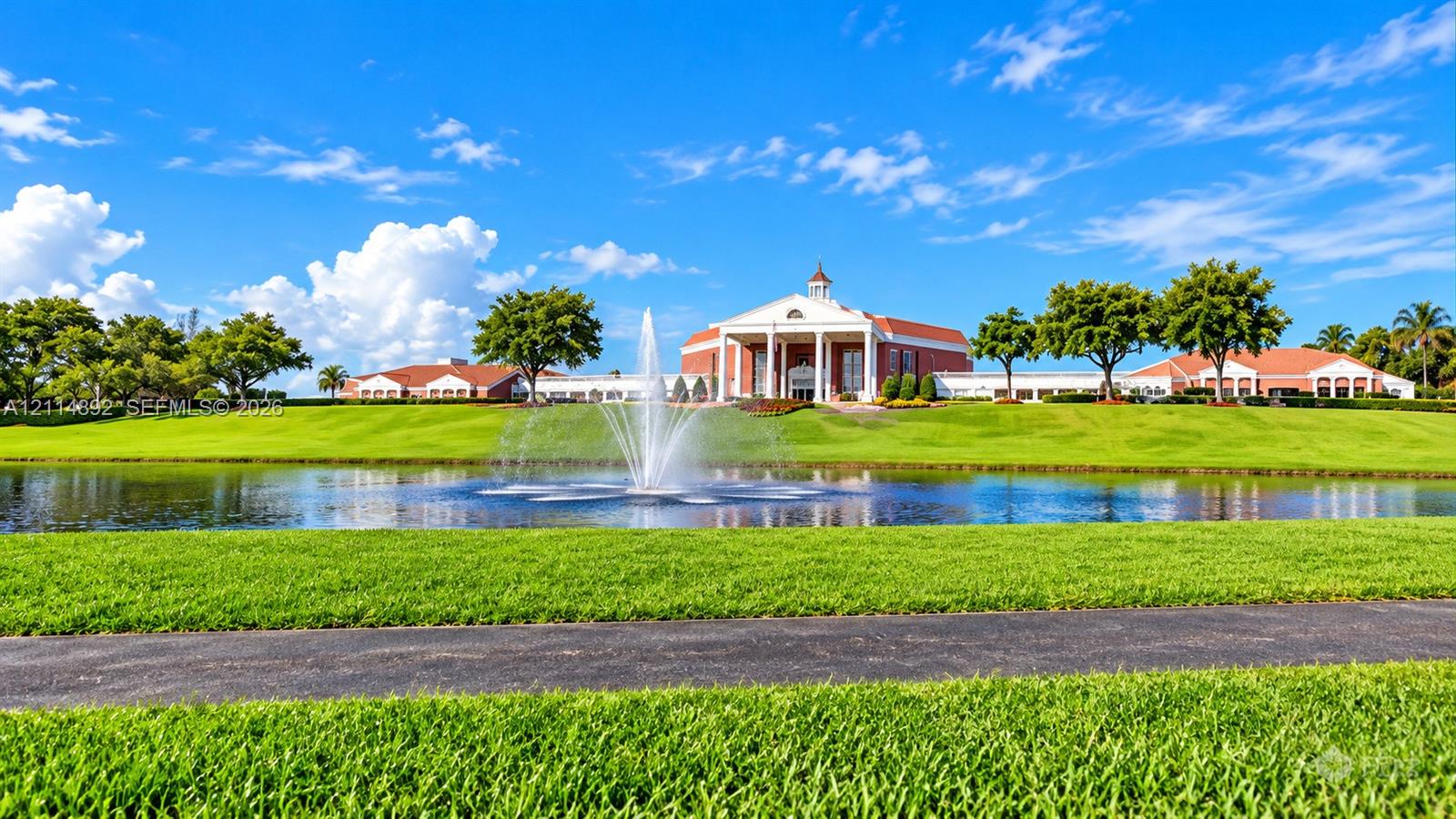 Grand architectural exterior featuring a pedimented facade, prominent central columns, a cupola, and extensive manicured grounds surrounding a central water feature with a fountain