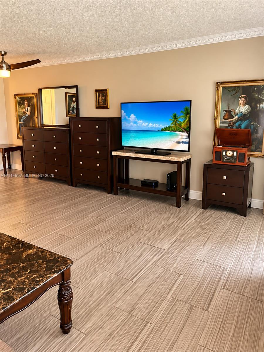 Neutral interior featuring wood-finish tile flooring, decorative crown molding, and a ceiling fan with integrated lighting