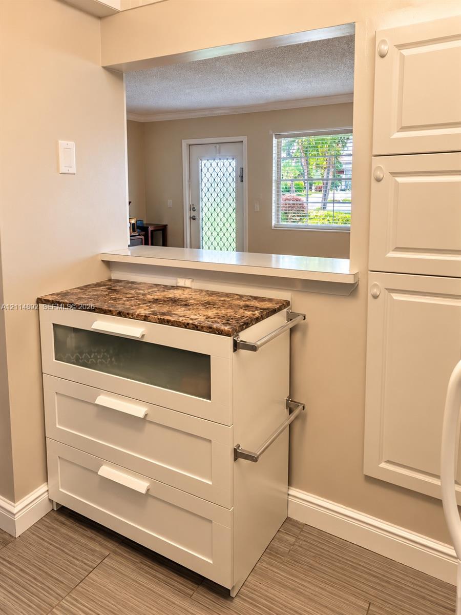 Custom cabinetry featuring a glass-panel drawer, stone-finish countertop, side-mounted metallic hardware, and integrated full-height storage cabinetry