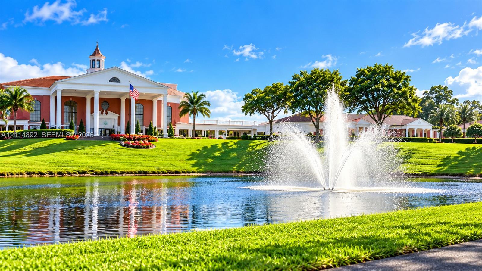 Neoclassical architecture featuring a prominent portico with grand columns, a centralized cupola, manicured landscaping, and a large central water fountain on a pond