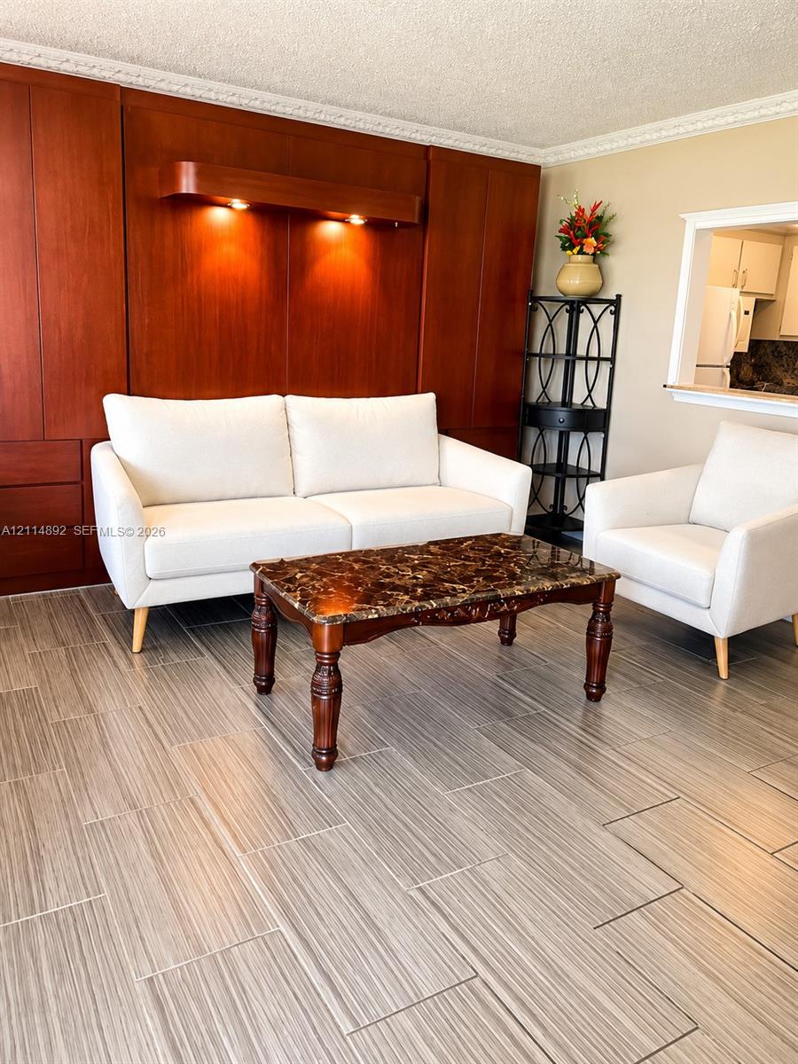 Floor-to-ceiling wood cabinetry featuring integrated recessed lighting, ceramic tile flooring, and a decorative crown molding finish