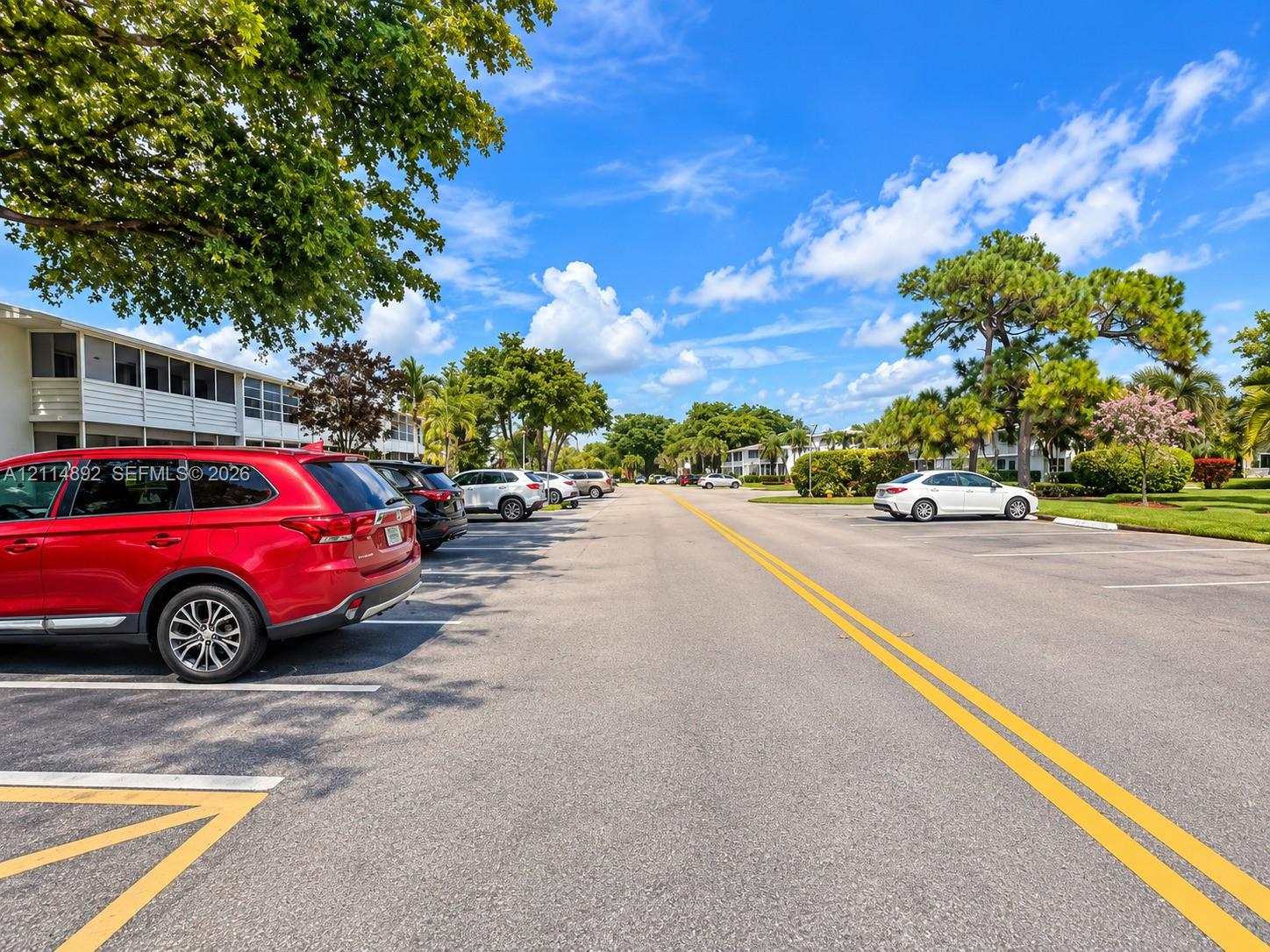 Paved surface parking area featuring marked spaces and mature shade trees
