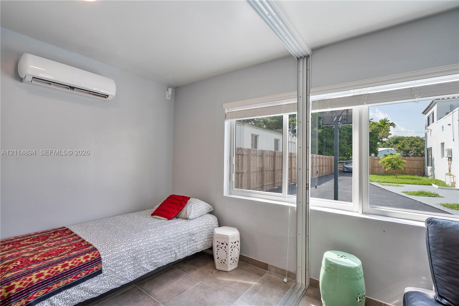 Wall-mounted climate control unit, large-format tile flooring, oversized windows with roller shades, and floor-to-ceiling mirror paneling
