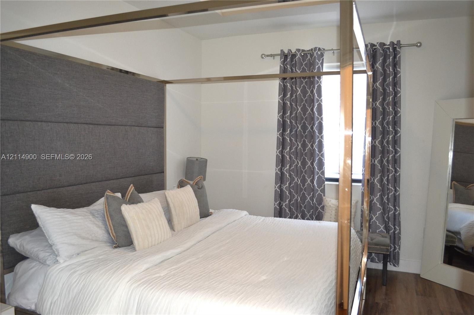 Wall-to-wall upholstered headboard featuring horizontal tufting and wood-finish flooring