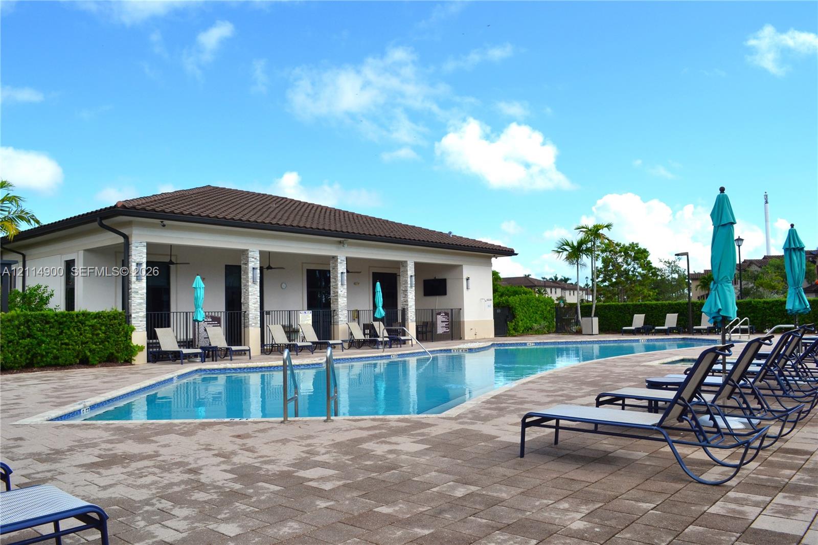 Outdoor swimming pool featuring a paved patio area, covered pavilion with stone-accented columns, and professional landscaping