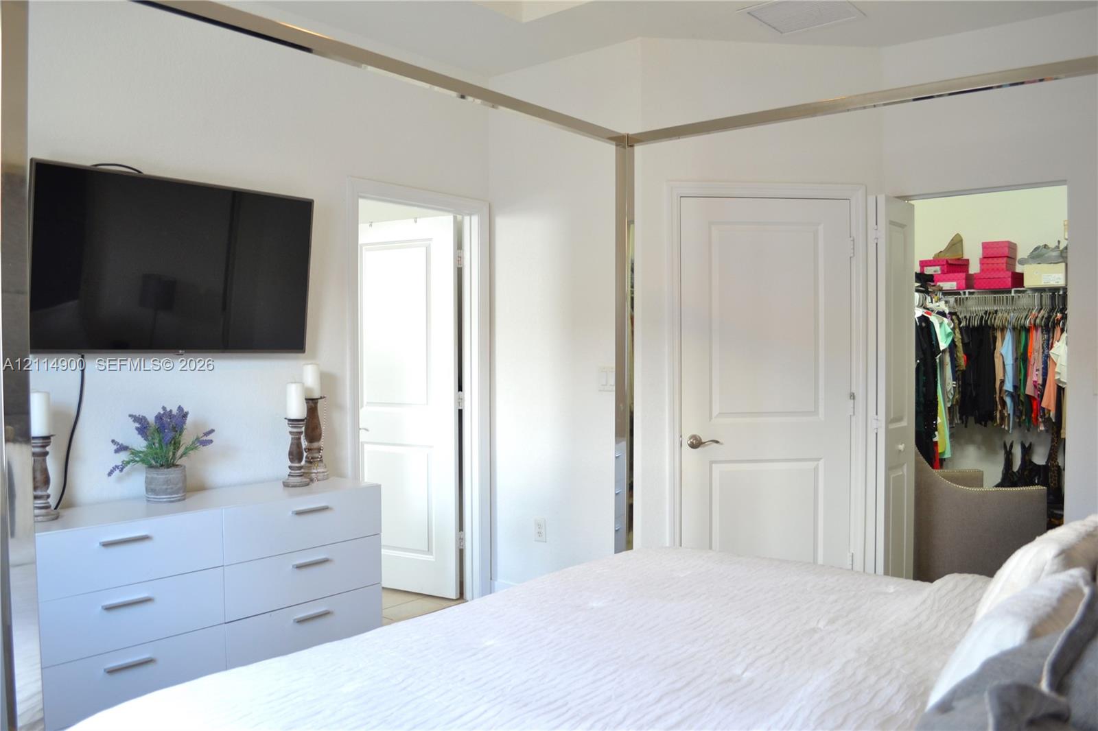 Interior space featuring white paneled doors, mirrored wall trim, and a dedicated walk-in closet with built-in wire shelving