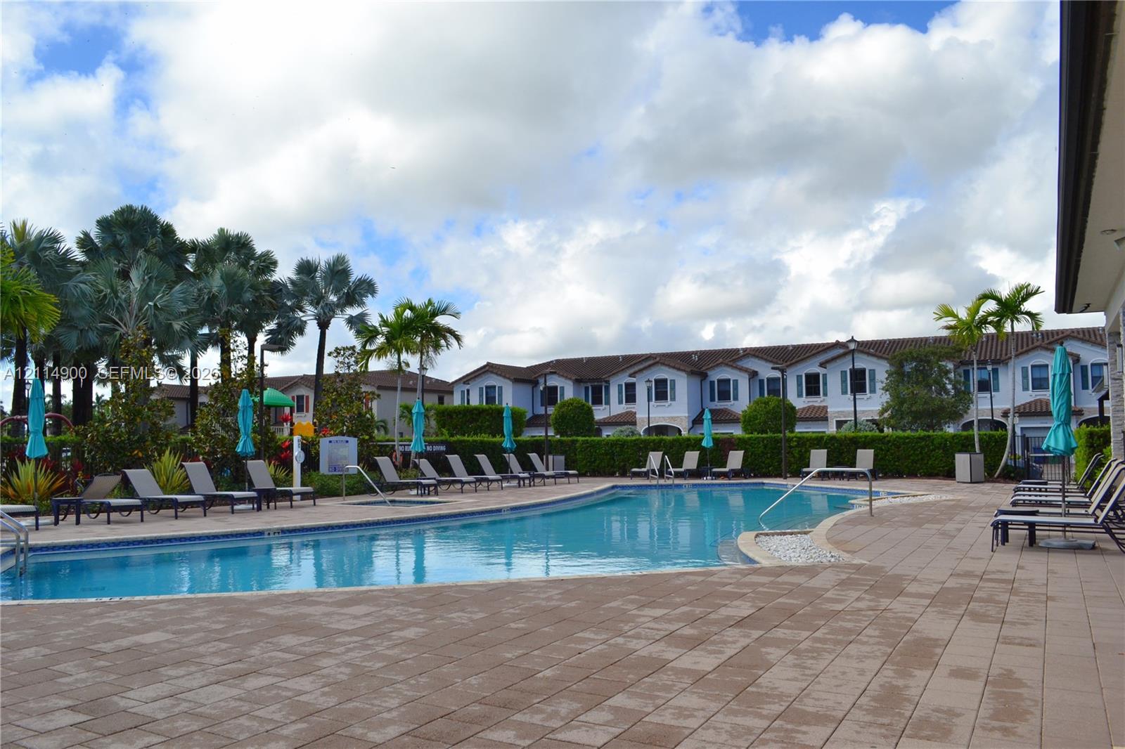 Swimming pool with a paved deck, perimeter landscaping, and metal handrails