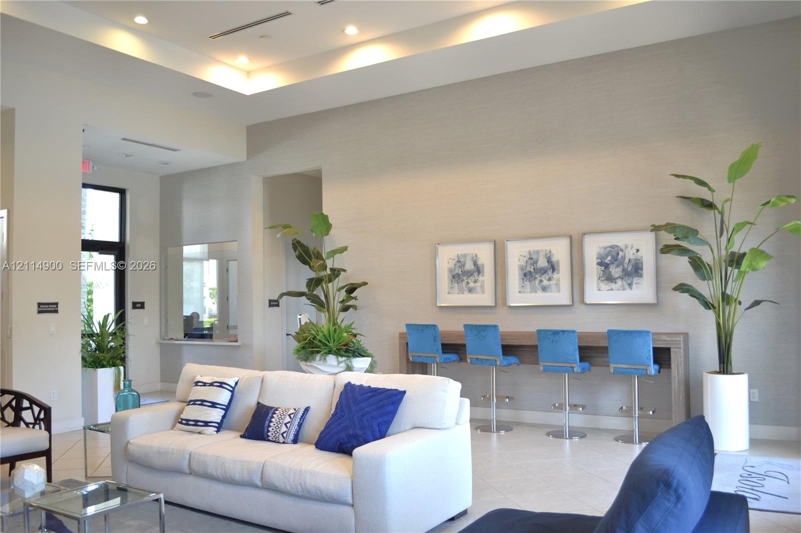 Tray ceiling with integrated lighting, textured wall finishes, recessed lighting, and large-format tile flooring