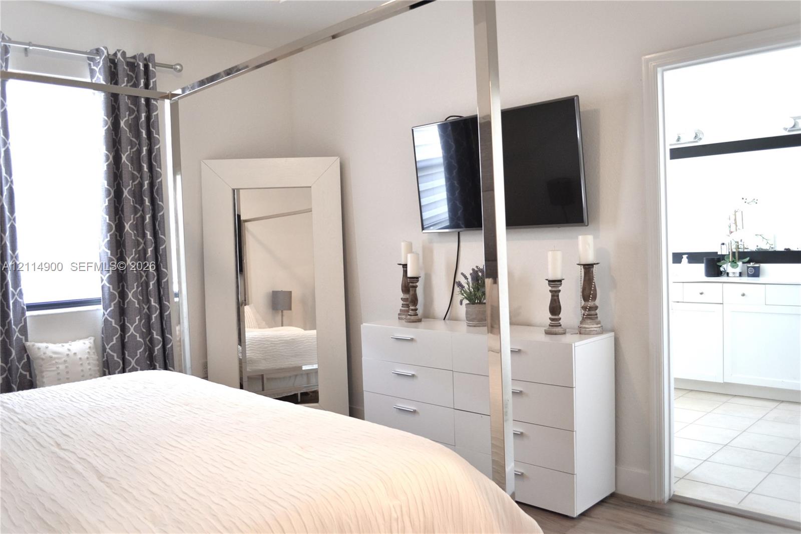 Neutral-toned room featuring light-colored wood-finish flooring, a metal-framed canopy structure, and an entryway with tile flooring