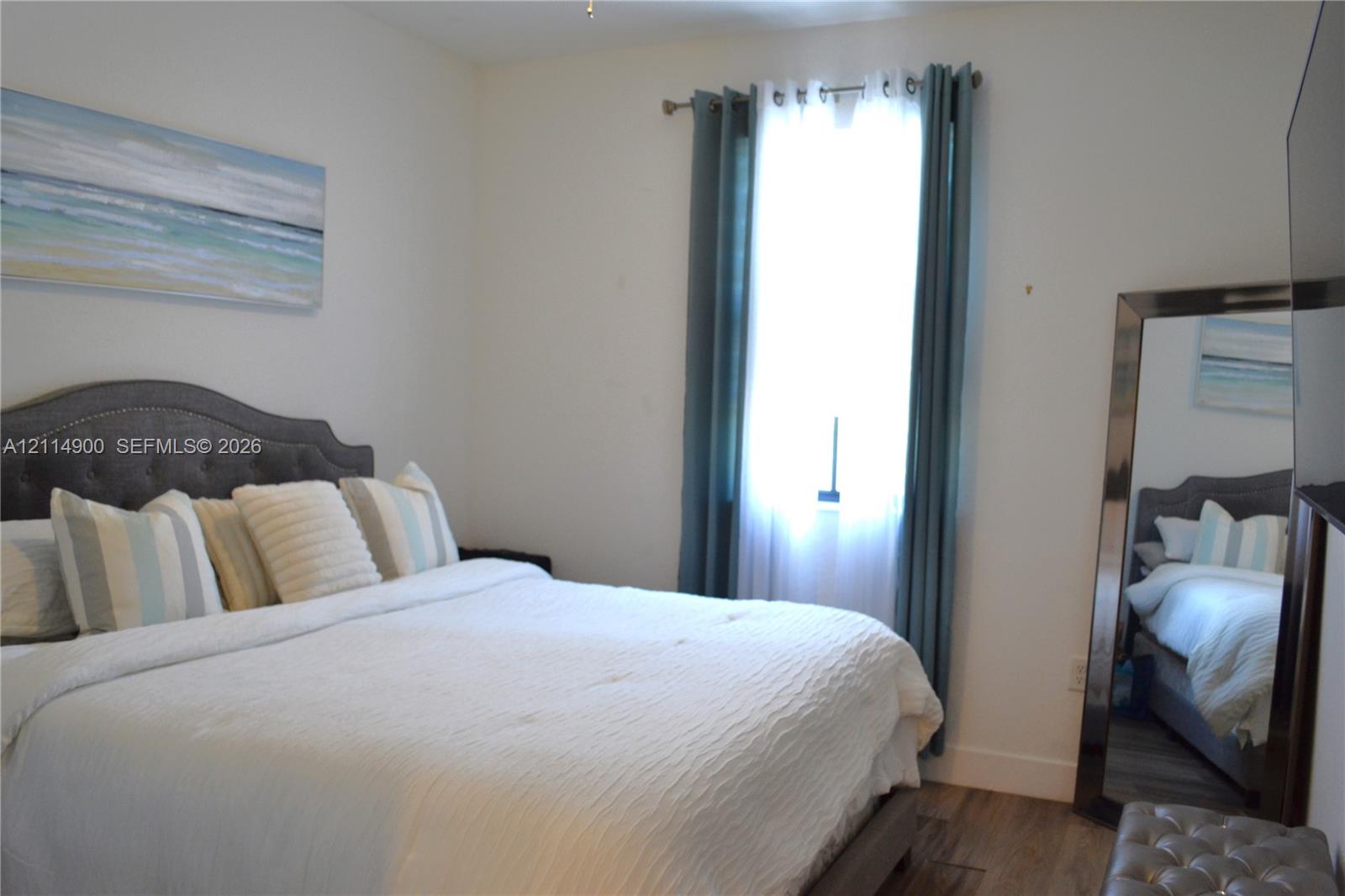 Wood-finish flooring and a single window with installed curtain rods