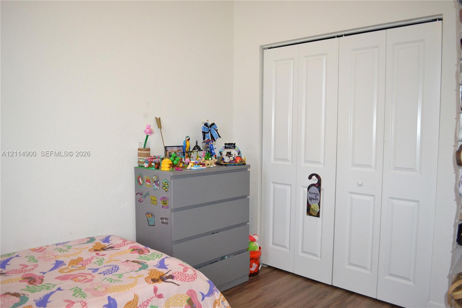 Bi-fold closet doors with white finish and wood-finish flooring