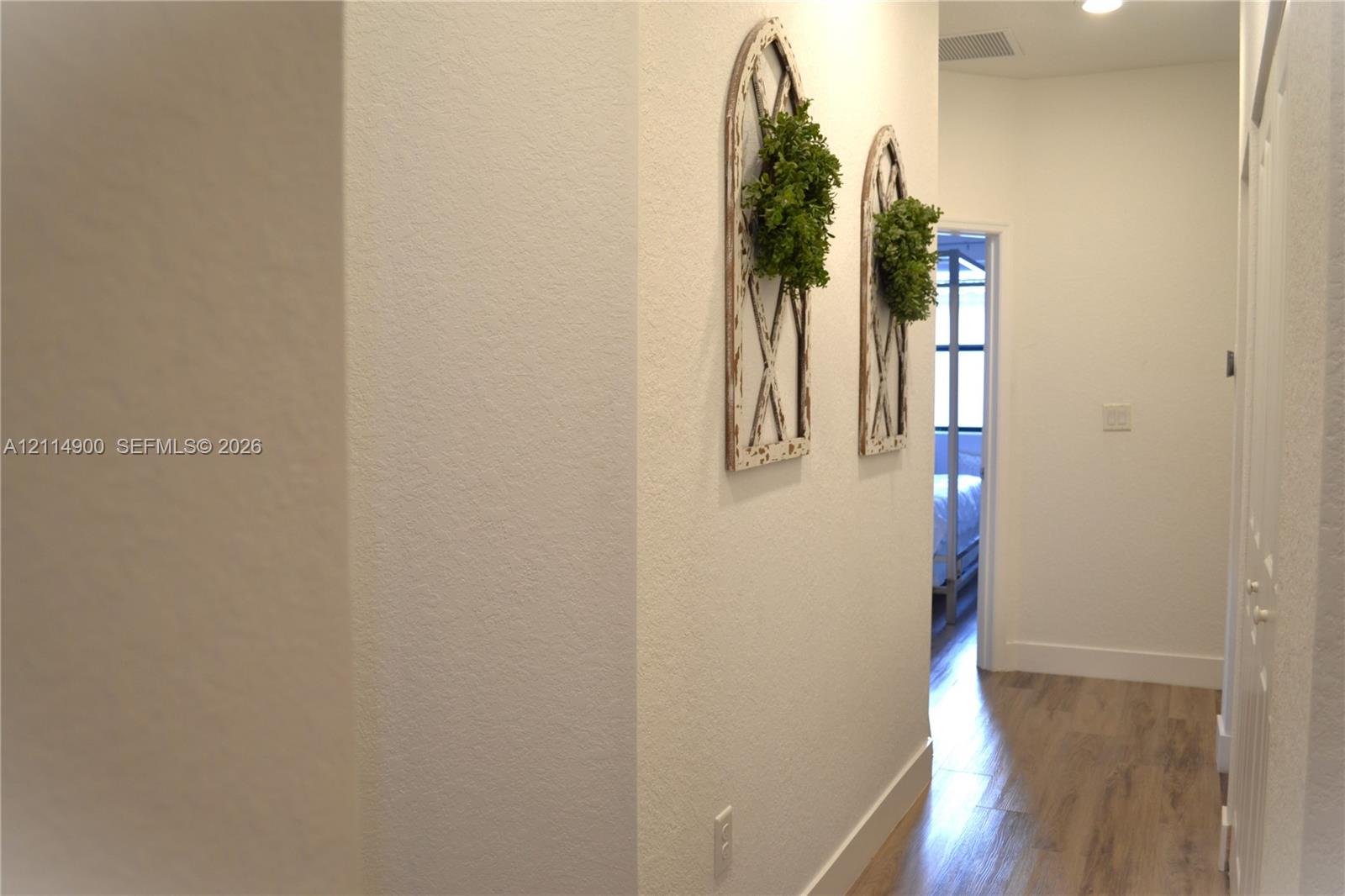 Hallway featuring wood-finish flooring, smooth-textured walls, and recessed ceiling lighting