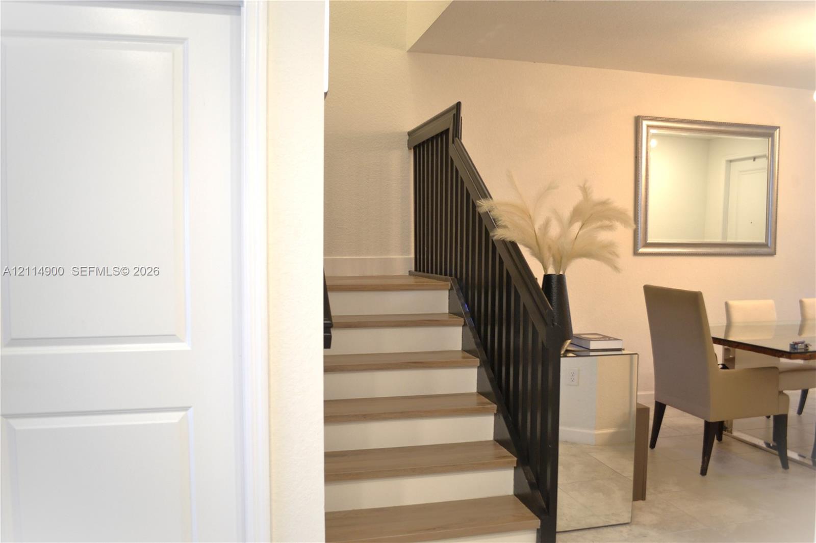 Staircase featuring light-tone wood treads, white risers, and a contrasting dark-finish handrail with vertical balusters