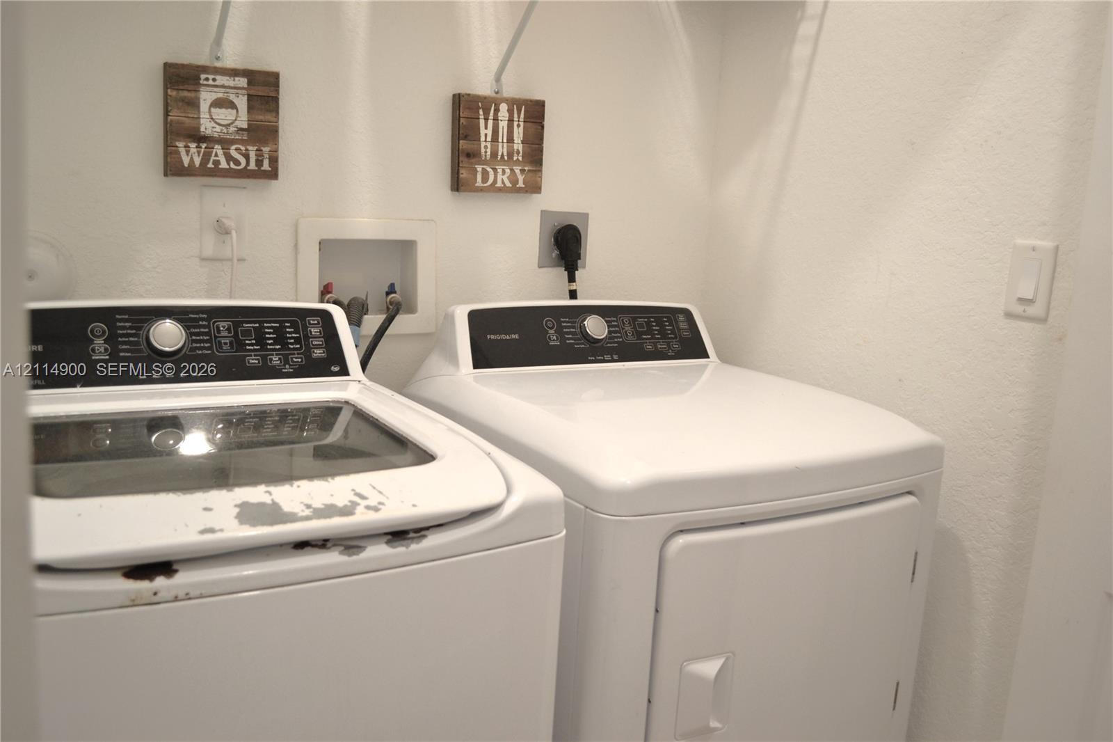Laundry alcove featuring recessed water supply connections, dedicated electrical outlets, and built-in upper shelving