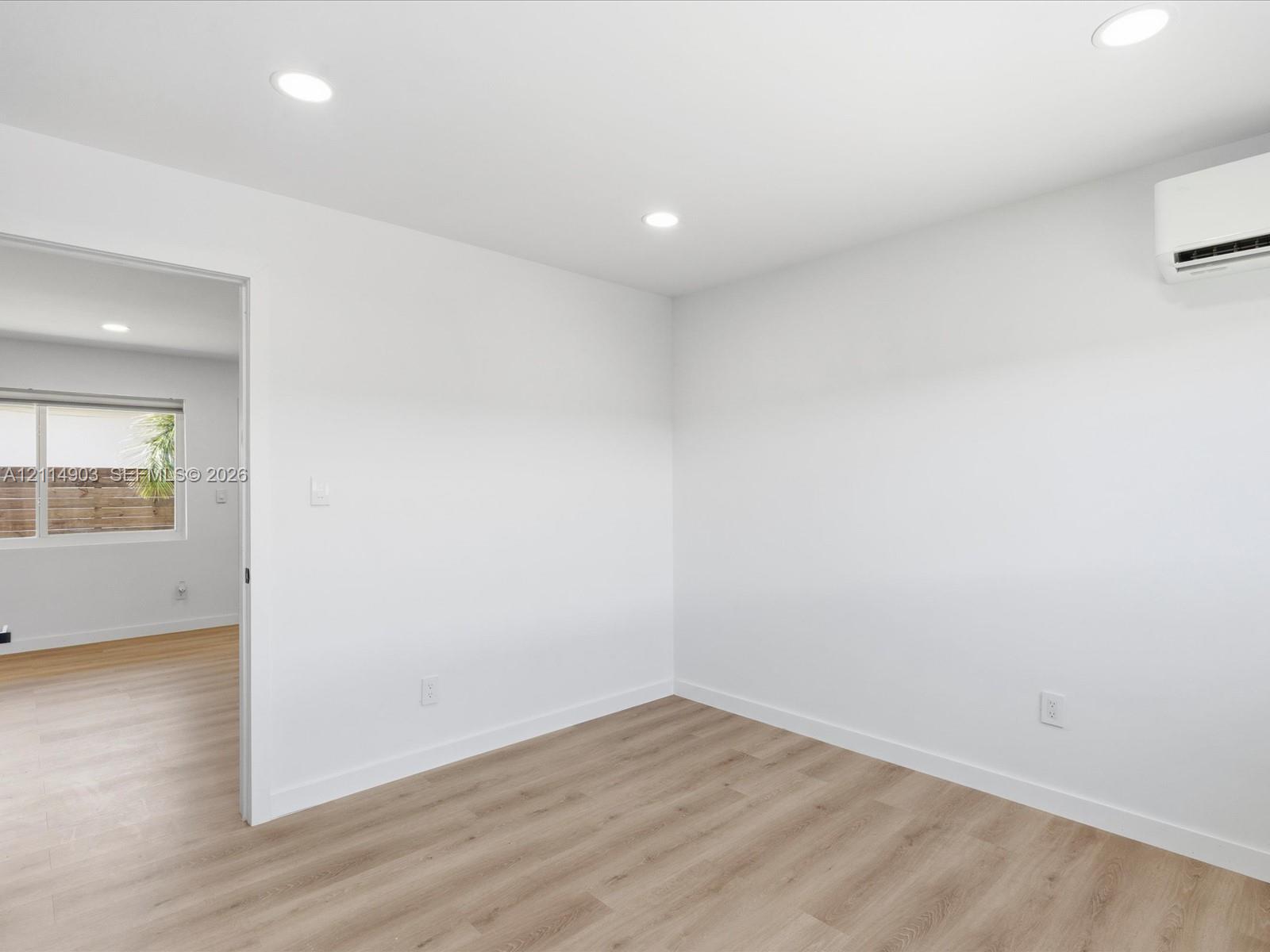 Interior space featuring wood-finish flooring, recessed lighting, and a wall-mounted ductless climate control unit