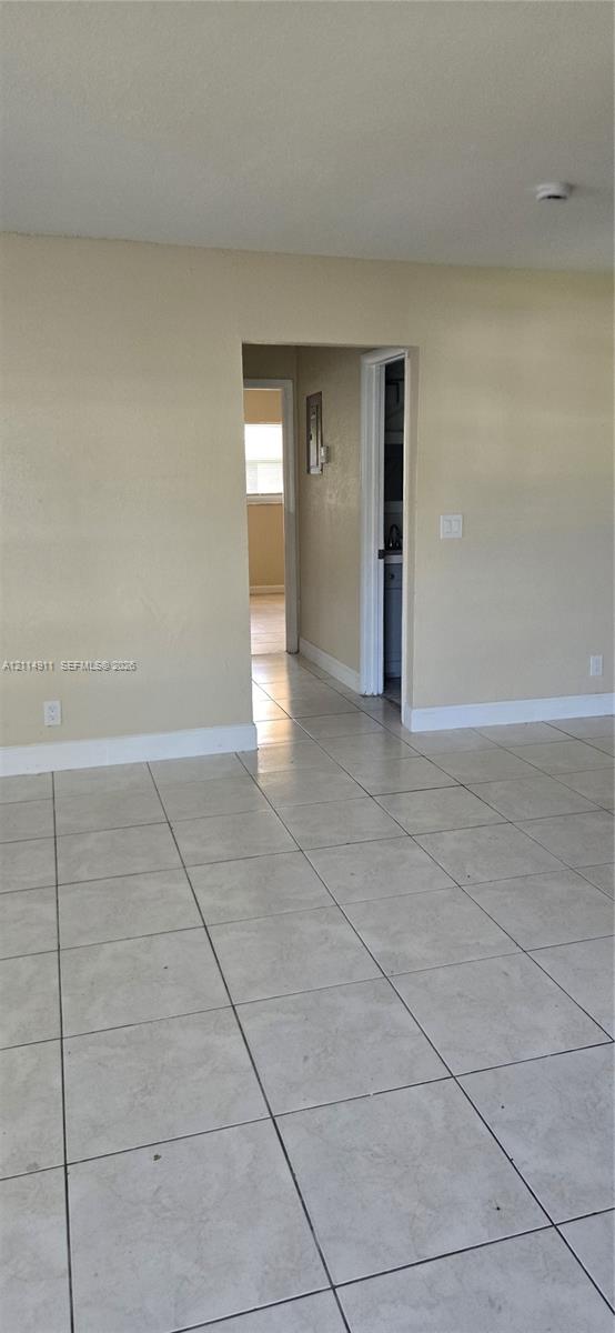 Neutral-toned interior featuring large-format ceramic tile flooring and a doorway leading to a secondary area