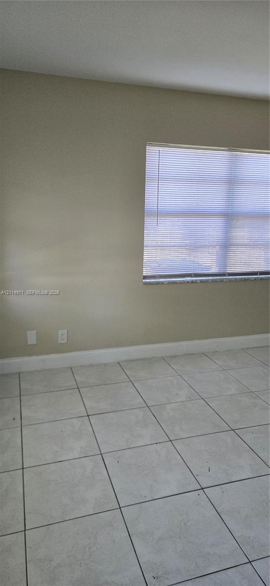 Neutral-toned interior walls featuring large-format ceramic tile flooring and a window with integrated blinds