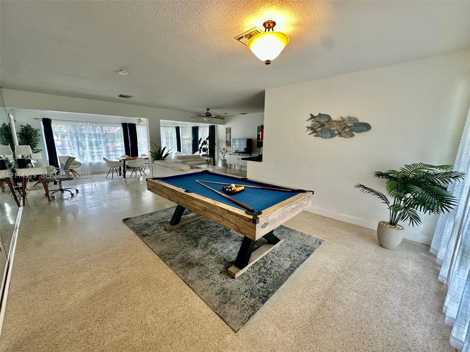 Open-concept interior featuring light-toned terrazzo flooring, expansive floor-to-ceiling windows, and a warm-toned flush-mount ceiling light fixture