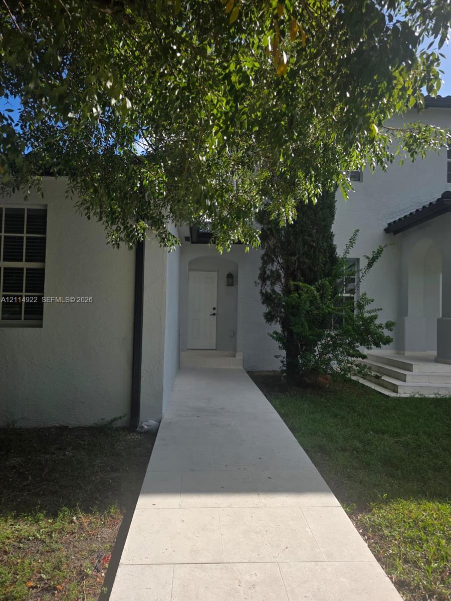 Stucco exterior featuring a paved walkway, covered entryway, and multi-pane grid windows Stucco exterior featuring a paved walkway, covered entryway, and multi-pane grid windows